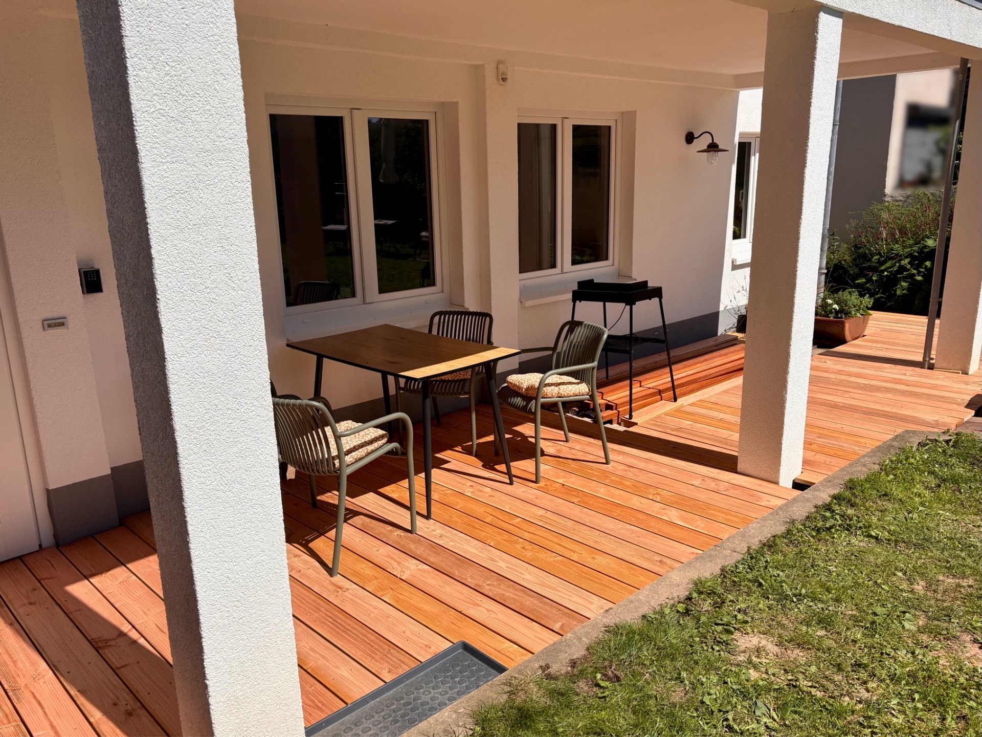 Sonnige Terrasse mit Esstisch und Gartenzugang